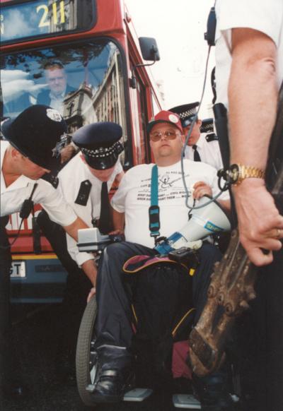 Protestor Chris Hughes had attached himself to a public bus during a DAN protest. Here we see police trying to release him. The exact date is unknown, but likely to be in 1994/5.