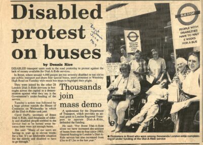 A clipping from a newspaper. The image shows a group of disabled people holding banners which read 