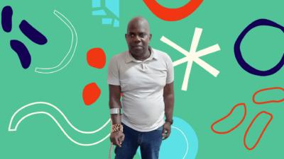 A photograph of Folaranmi. He is a Black, bald man wearing a white polo shirt and blue jeans. He uses a crutch on his right arm. The photo stands against a green background, with a white, red, and blue pattern.