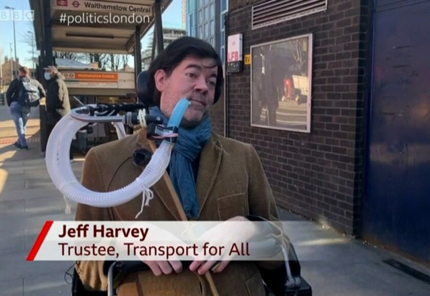 Jeff, a white man with dark brown hair who is wearing a corduroy blazer and sat in an electric wheelchair using a breathing apparatus, is outside Walthamstow Tube station speaking to the camera about step-free access. The aston reads “Jeff Harvey, Trustee, Transport For All’