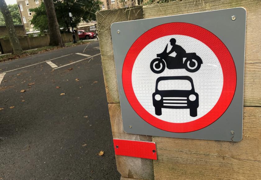 A traffic sign with a graphic of a motorbike and a car inside a white circle with a red border